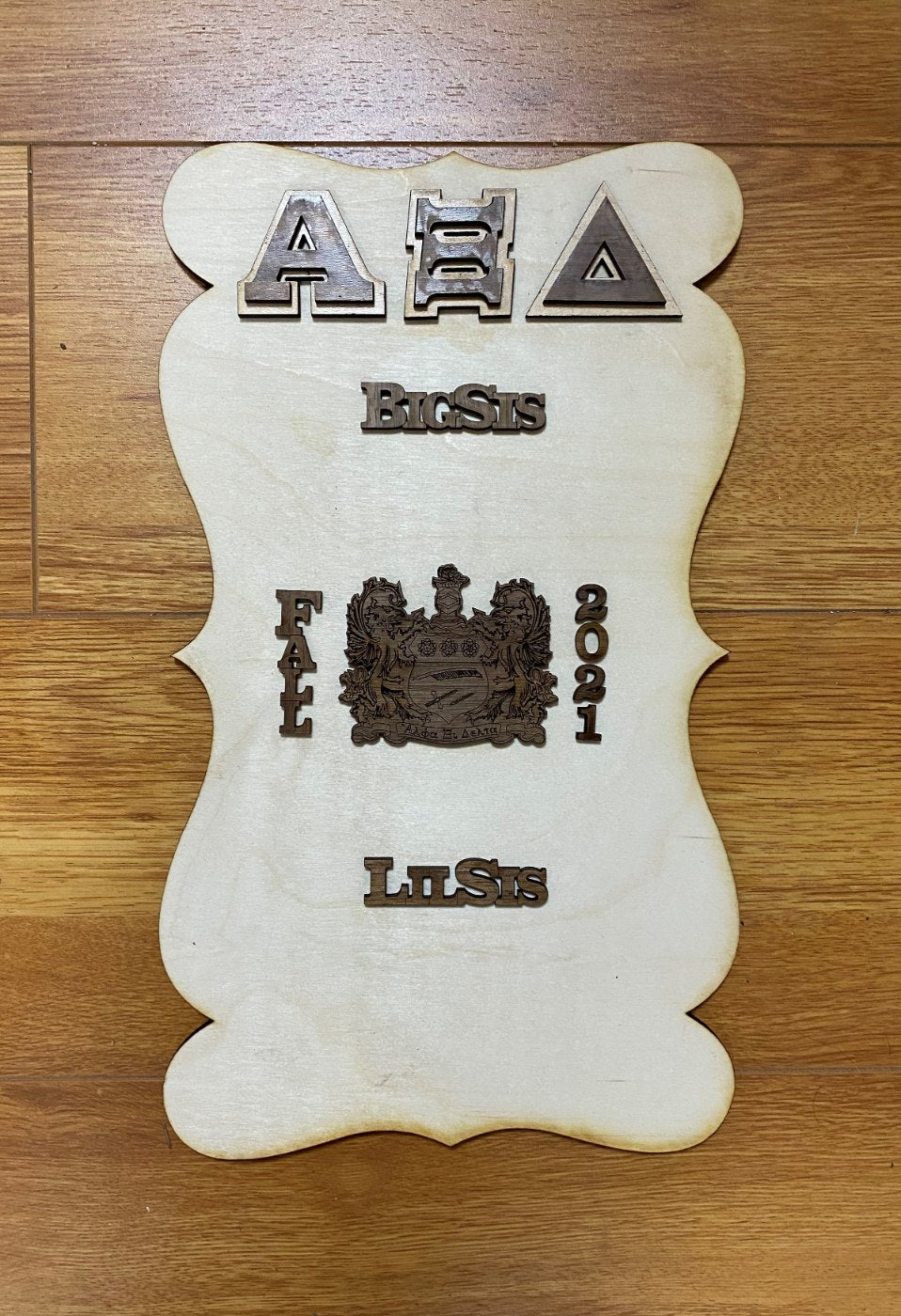 Example only: a finished plaque decorated with letters, a crest, and symbols. Each piece is sold separately.