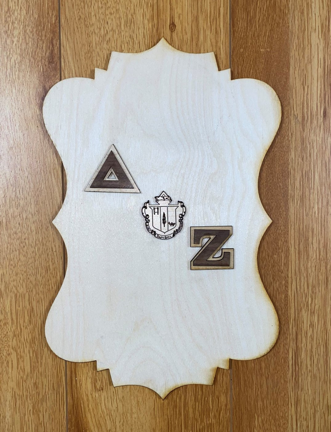 Example only: a finished plaque decorated with letters, a crest, and symbols. Each piece is sold separately.